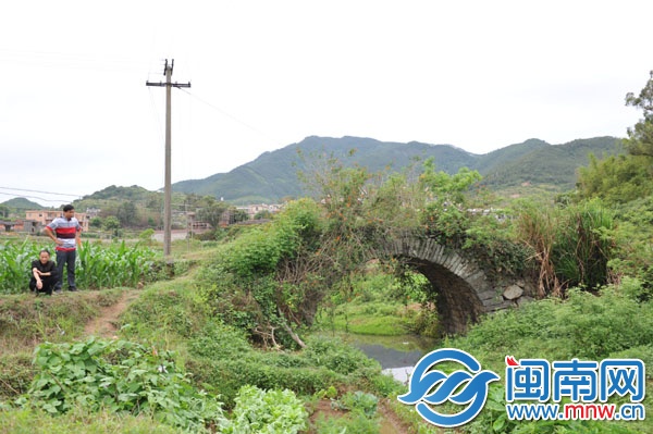 已廢棄的石拱橋，被野草覆蓋，下有溪流，村民稱此路